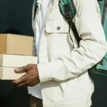 Kurir memegang paket karton di luar ruangan sebagai ilustrasi layanan pengiriman sameday di kota