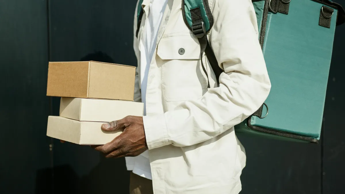 Kurir memegang paket karton di luar ruangan sebagai ilustrasi layanan pengiriman sameday di kota